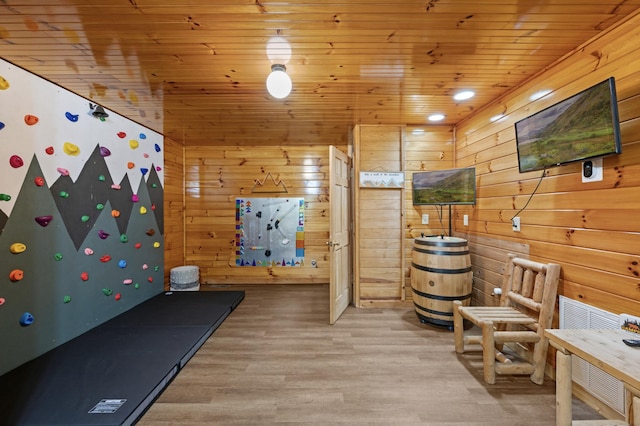 exercise room featuring light hardwood / wood-style flooring, wooden ceiling, and wood walls