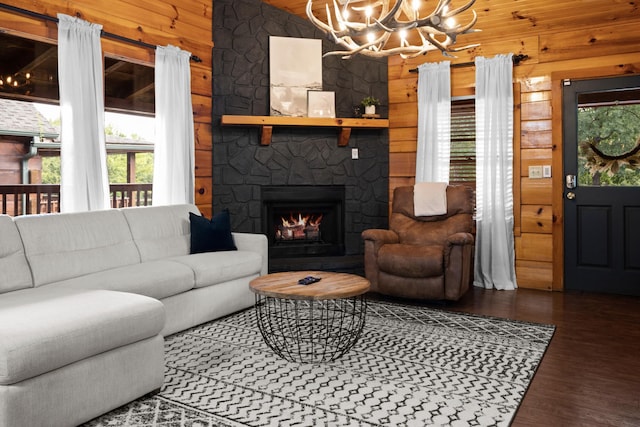 living room featuring a stone fireplace, dark wood-type flooring, a healthy amount of sunlight, and wood walls