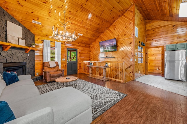 living room featuring a stone fireplace, high vaulted ceiling, hardwood / wood-style flooring, wooden ceiling, and an inviting chandelier