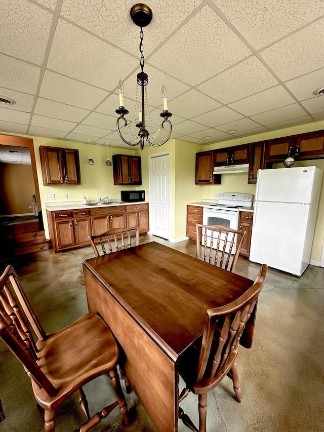 dining area featuring sink, a drop ceiling, and an inviting chandelier