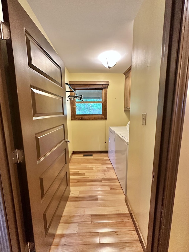 laundry area with washer and clothes dryer, cabinets, and light hardwood / wood-style flooring