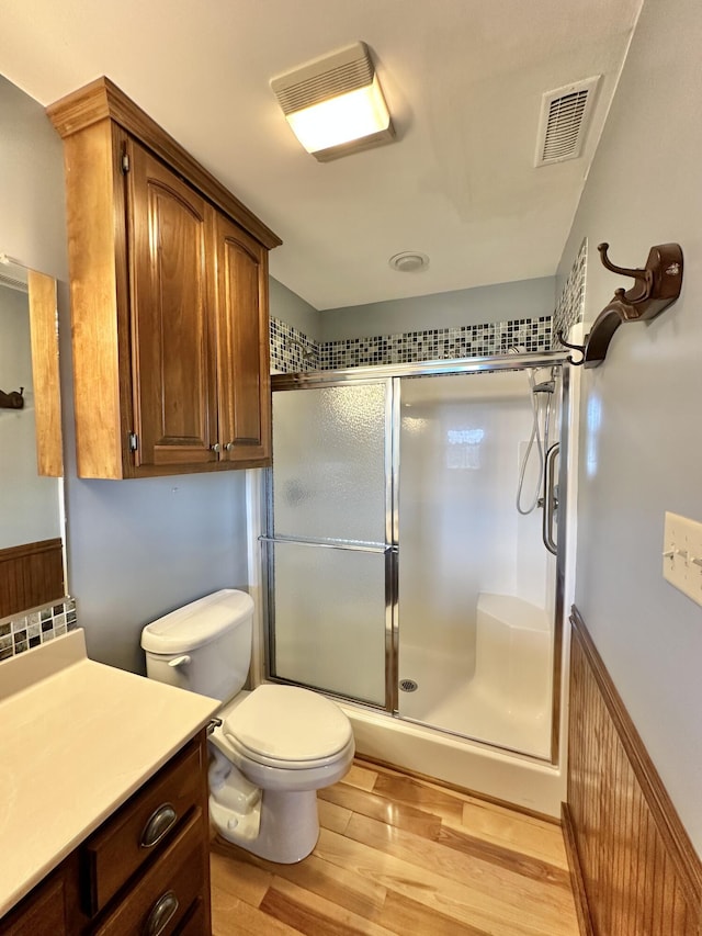 bathroom with hardwood / wood-style floors, vanity, toilet, and walk in shower