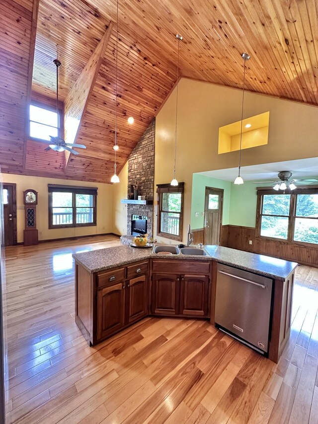 kitchen featuring dishwasher, decorative light fixtures, high vaulted ceiling, and a kitchen island with sink