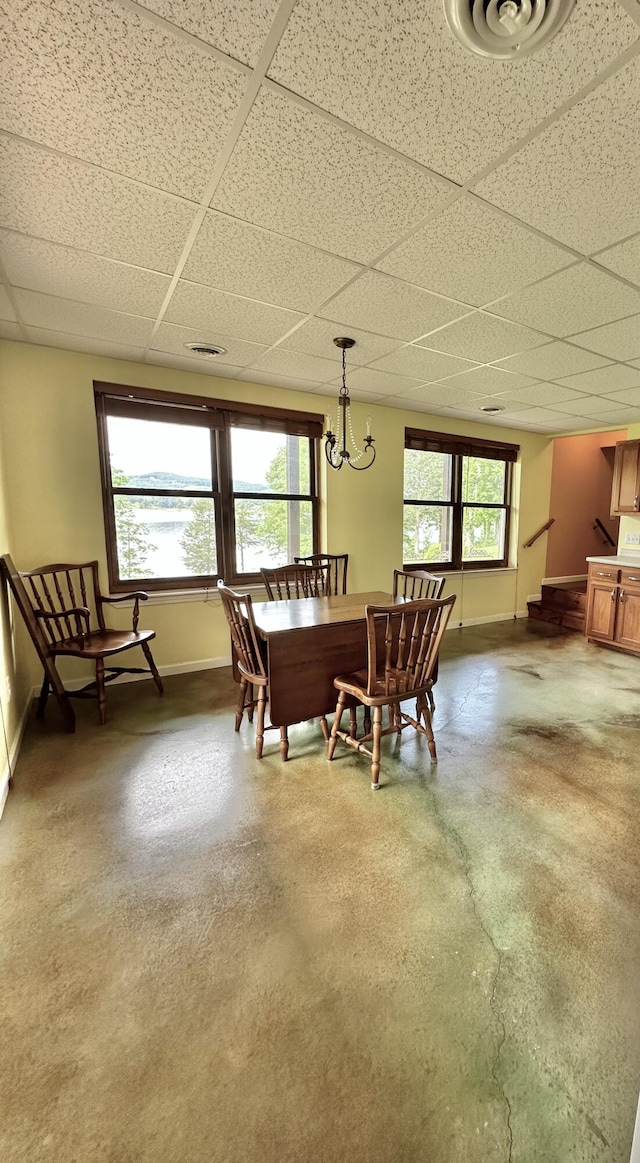 dining area with concrete flooring, a drop ceiling, and a healthy amount of sunlight