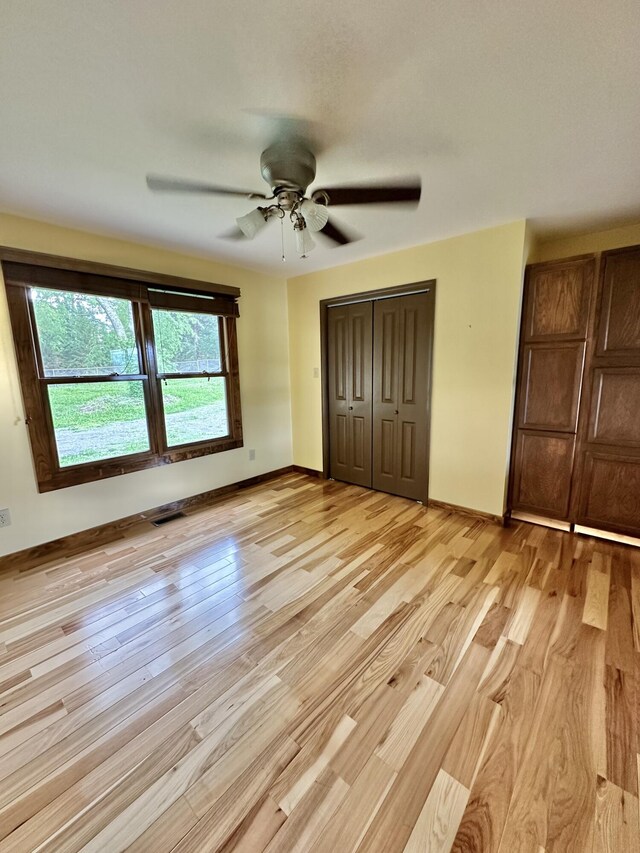 unfurnished bedroom featuring ceiling fan, a closet, and light wood-type flooring