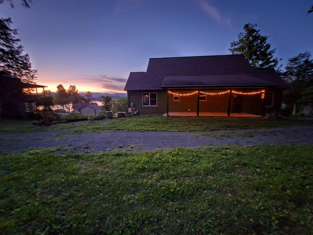 back house at dusk with a lawn