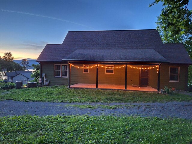 back house at dusk featuring a patio and central AC