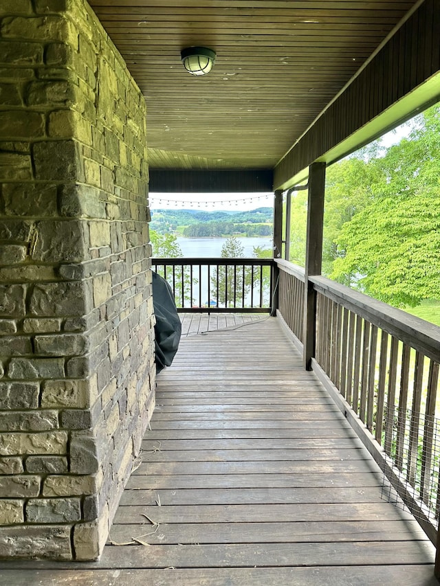 wooden deck featuring grilling area, a water view, and a porch