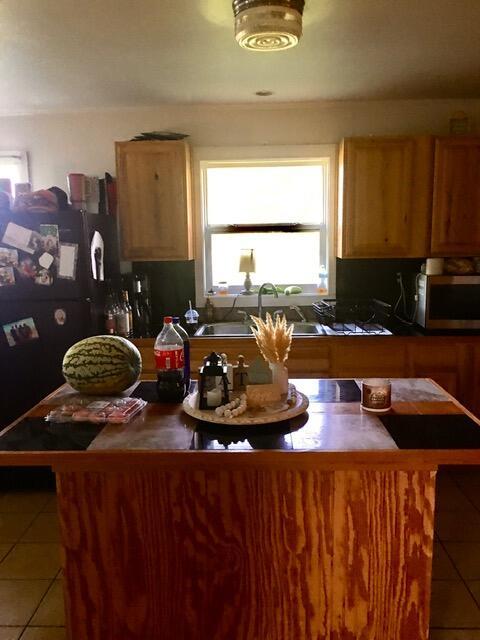 kitchen featuring black refrigerator, light tile patterned floors, and sink