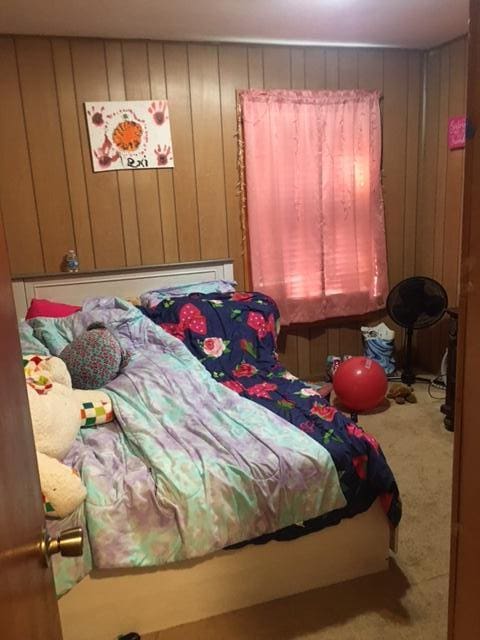 bedroom with carpet floors and wooden walls