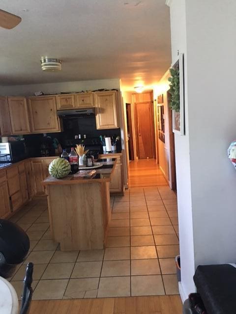 kitchen featuring a center island, light brown cabinets, light tile patterned floors, and extractor fan