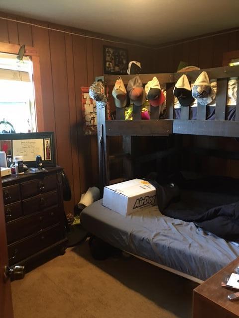 carpeted bedroom featuring wood walls