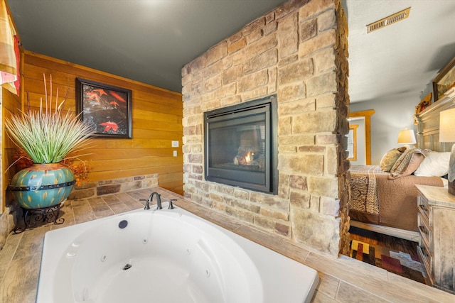 bathroom with a stone fireplace and a bathtub