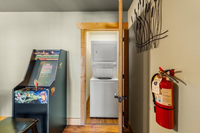 clothes washing area with stacked washer / dryer and hardwood / wood-style floors