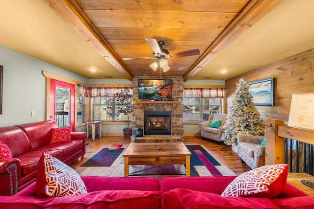 living room with wood ceiling, ceiling fan, wooden walls, wood-type flooring, and a stone fireplace