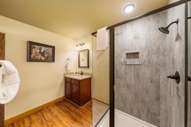 bathroom featuring vanity, hardwood / wood-style floors, and a tile shower