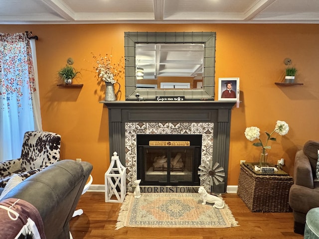 sitting room with a tiled fireplace, ornamental molding, coffered ceiling, and hardwood / wood-style flooring