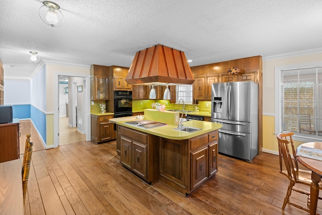 kitchen with a center island with sink, appliances with stainless steel finishes, light countertops, and dark wood-style flooring