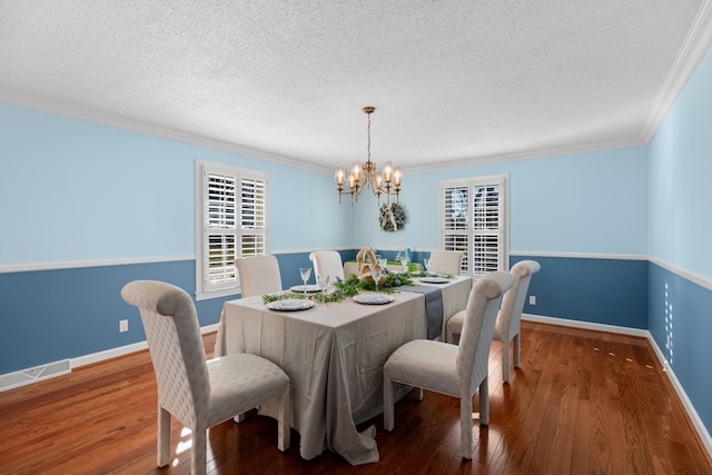 dining area with visible vents, baseboards, hardwood / wood-style flooring, crown molding, and a notable chandelier