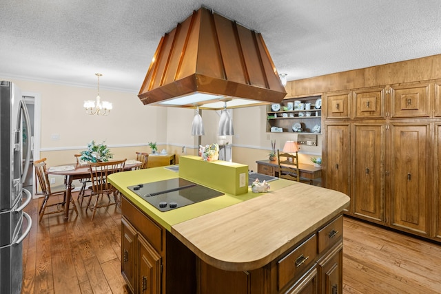 kitchen with black electric stovetop, stainless steel fridge, light wood finished floors, and island range hood