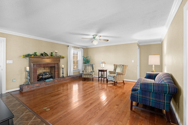 living area featuring a textured ceiling, ornamental molding, a brick fireplace, and wood finished floors