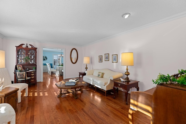 living area featuring a textured ceiling, ornamental molding, wood finished floors, and baseboards