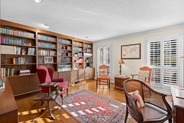 sitting room with ornamental molding, wood-type flooring, and a wealth of natural light