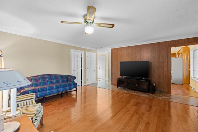 living area with ceiling fan, crown molding, a textured ceiling, and wood finished floors