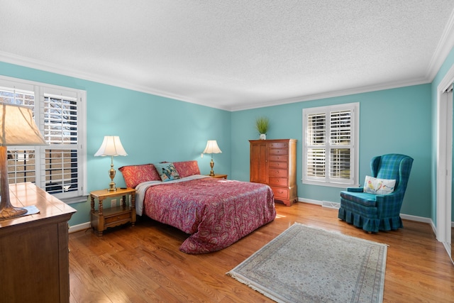 bedroom with ornamental molding, visible vents, a textured ceiling, and wood finished floors