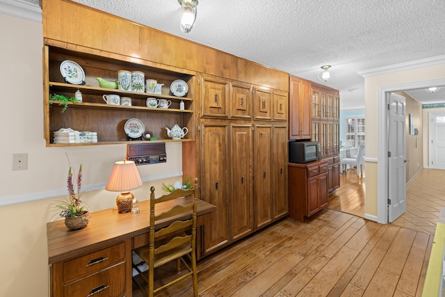 home office with light wood-style flooring, built in desk, and a textured ceiling