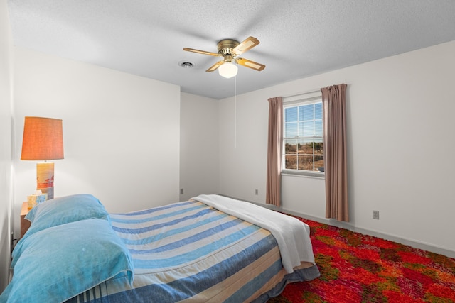 bedroom featuring baseboards, ceiling fan, visible vents, and a textured ceiling