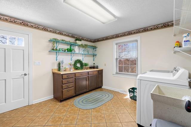 clothes washing area with visible vents, light tile patterned flooring, a textured ceiling, separate washer and dryer, and laundry area