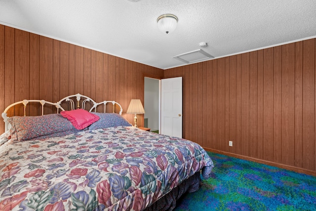 carpeted bedroom with attic access, wooden walls, and a textured ceiling