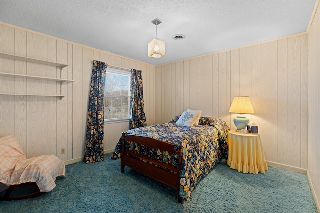 carpeted bedroom with a textured ceiling, baseboards, visible vents, and wooden walls