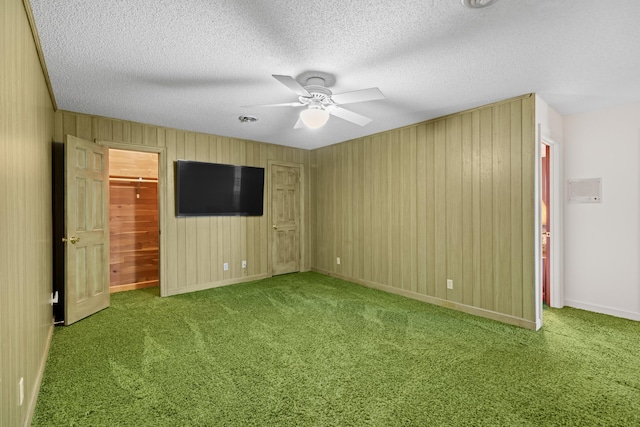 interior space with carpet, ceiling fan, a textured ceiling, and baseboards