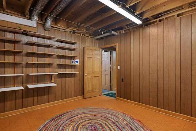 unfinished below grade area with wood walls and tile patterned floors