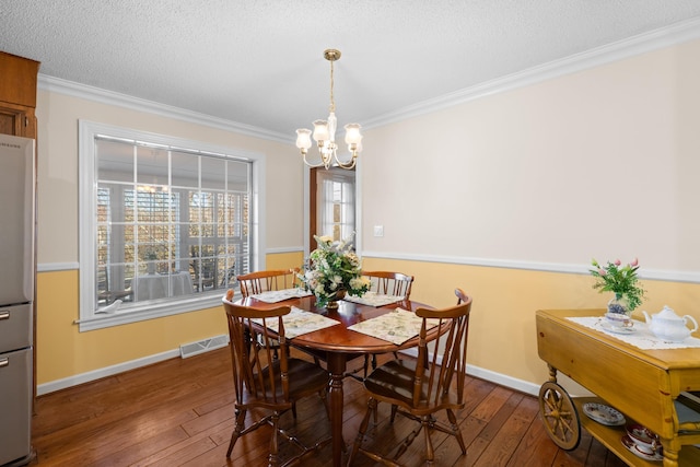 dining space featuring ornamental molding, visible vents, a textured ceiling, and hardwood / wood-style floors