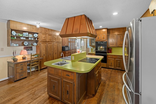 kitchen with a kitchen island with sink, a sink, custom exhaust hood, dark wood-style floors, and black appliances