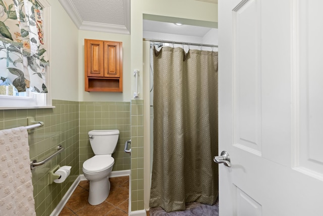 full bath featuring toilet, a wainscoted wall, tile patterned flooring, crown molding, and tile walls