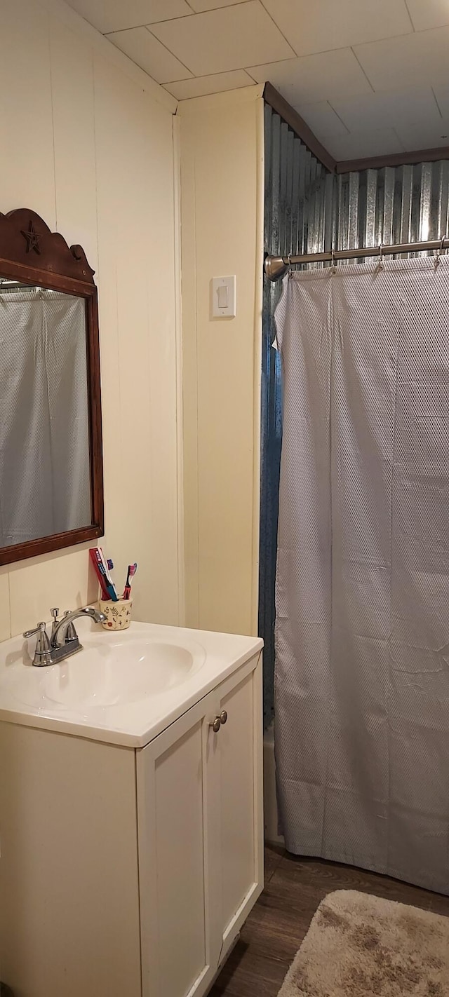 bathroom with vanity, shower / bathtub combination with curtain, and wood finished floors