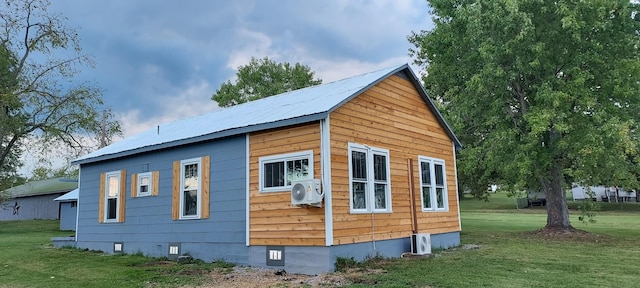 view of home's exterior with ac unit, a lawn, metal roof, an outdoor structure, and crawl space