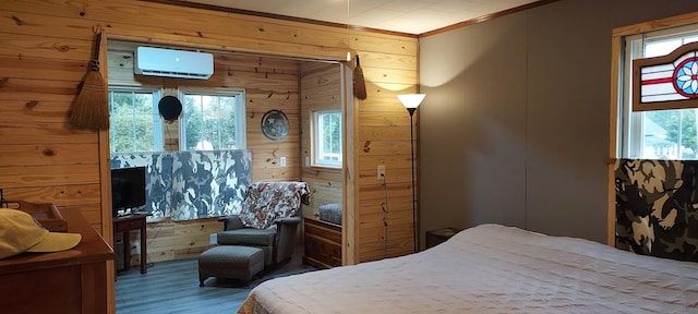 bedroom with wood finished floors, wood walls, a wall mounted air conditioner, and ornamental molding