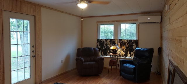 living area with ornamental molding, a ceiling fan, light wood finished floors, and a wall mounted AC