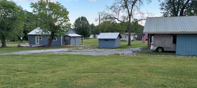 view of yard featuring a storage shed, an outdoor structure, and driveway