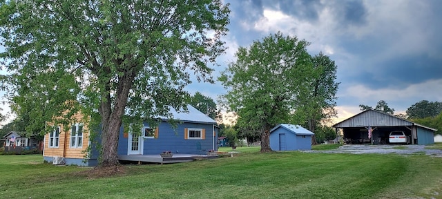 view of yard featuring a carport, an outdoor structure, and driveway