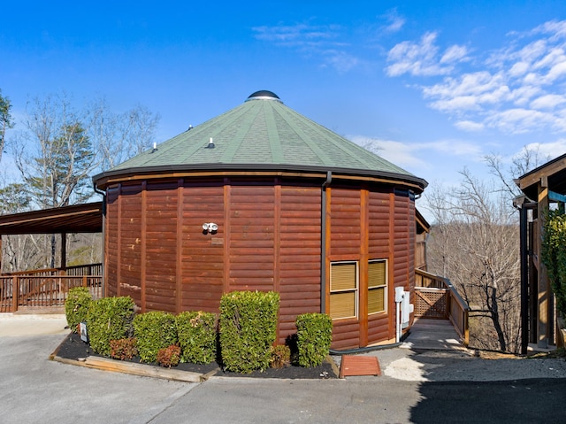 exterior space with a shingled roof and log veneer siding