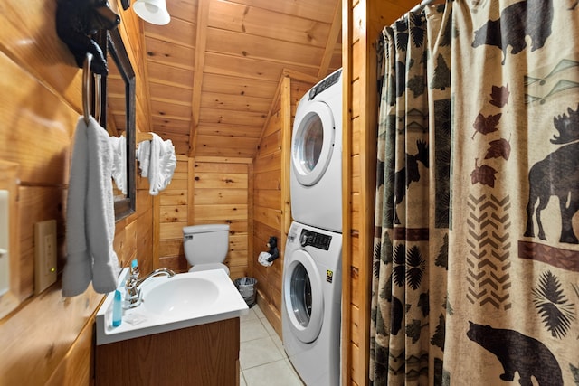 bathroom featuring stacked washer / drying machine, toilet, wooden walls, tile patterned flooring, and wooden ceiling