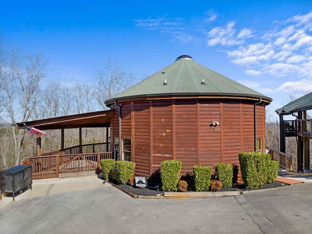 view of side of property featuring an attached carport and roof with shingles