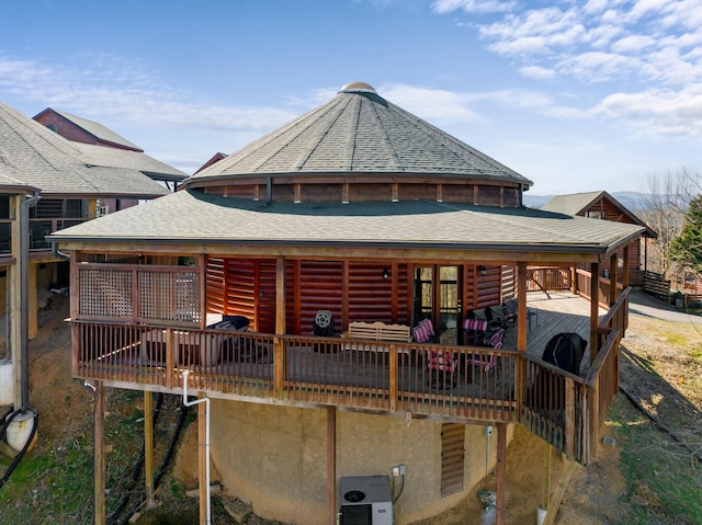 rear view of property with a shingled roof and a wooden deck