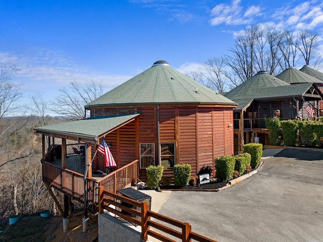 view of front of home featuring faux log siding and roof with shingles